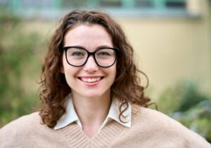 Young smiling professional business woman standing outdoor, headshot portrait.